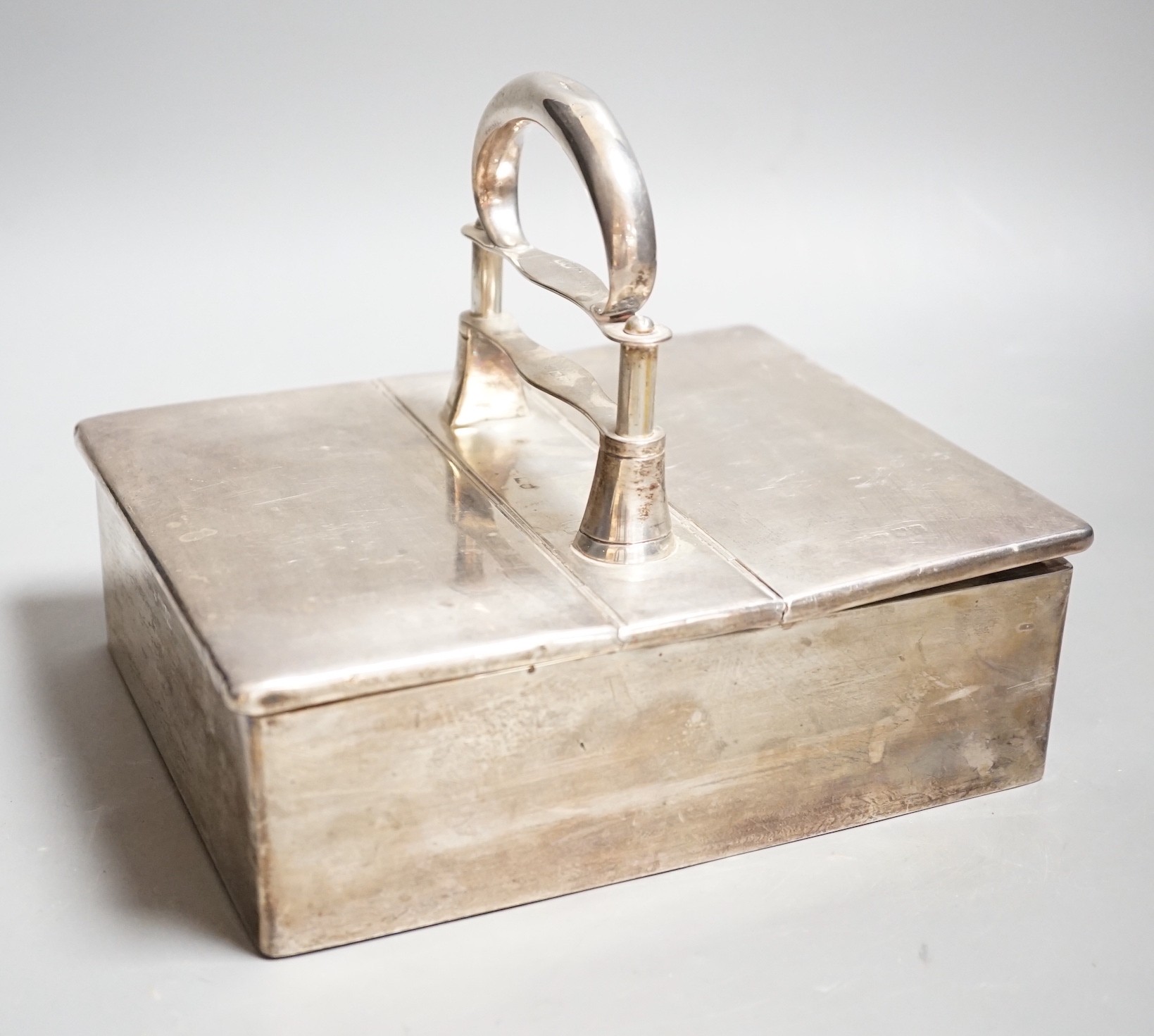 An Edwardian portable silver mounted two division cigar box, with patent action handle which when pushed downwards, raises the two covers (not currently working), maker Joseph Braham?, London, 1907, length 21cm.